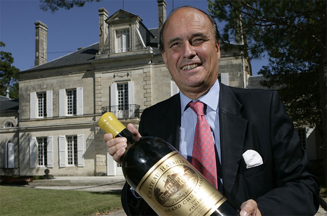 Frédéric Castéja smiles holding a large format bottle of Château Batailley Grand Cru Classé Pauillac outside the château building.