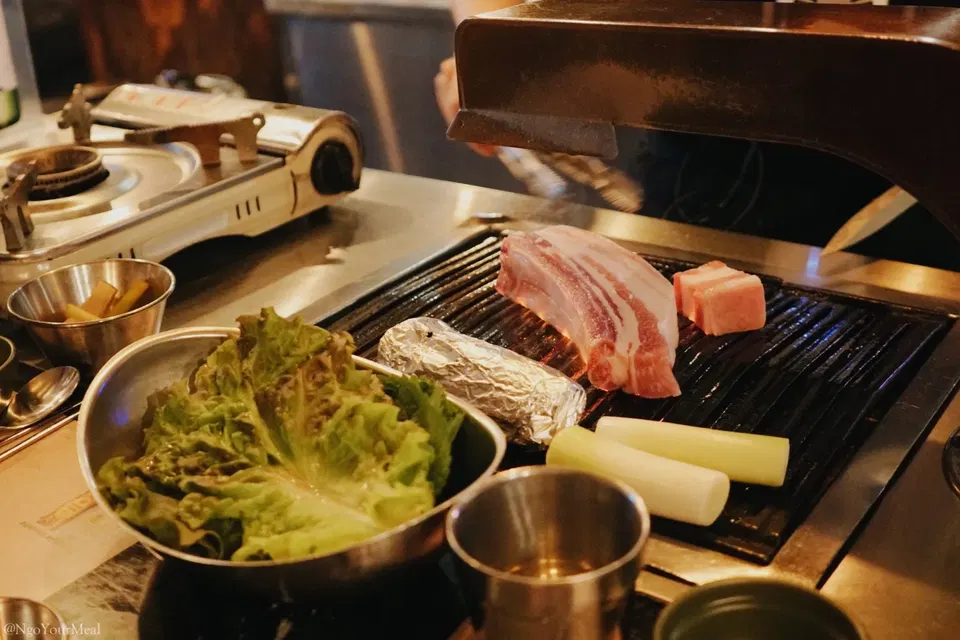 Geumdwaeji Sikdang's YBD pork belly and neck sizzle on the grill, ready for lettuce wraps.