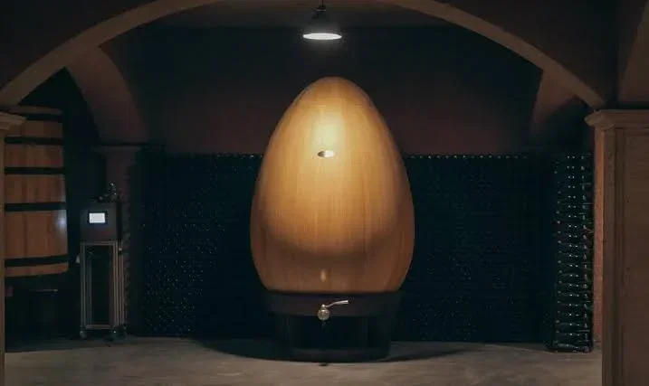 An egg-shaped oak aging vessel in a vaulted Champagne cellar.