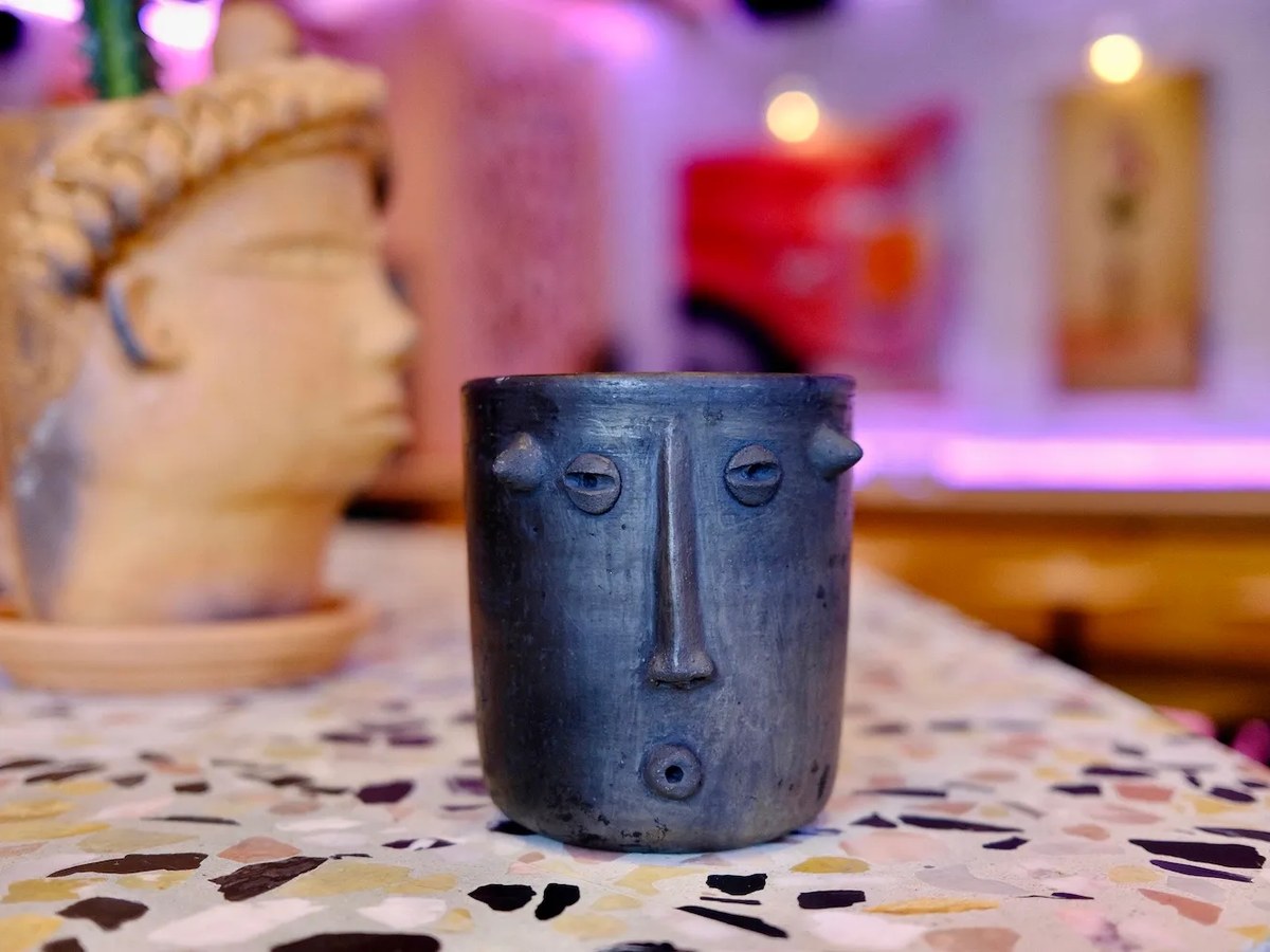 The Mole Negroni cocktail at Superbueno, served in a unique ceramic face mug on a terrazzo bar top.
