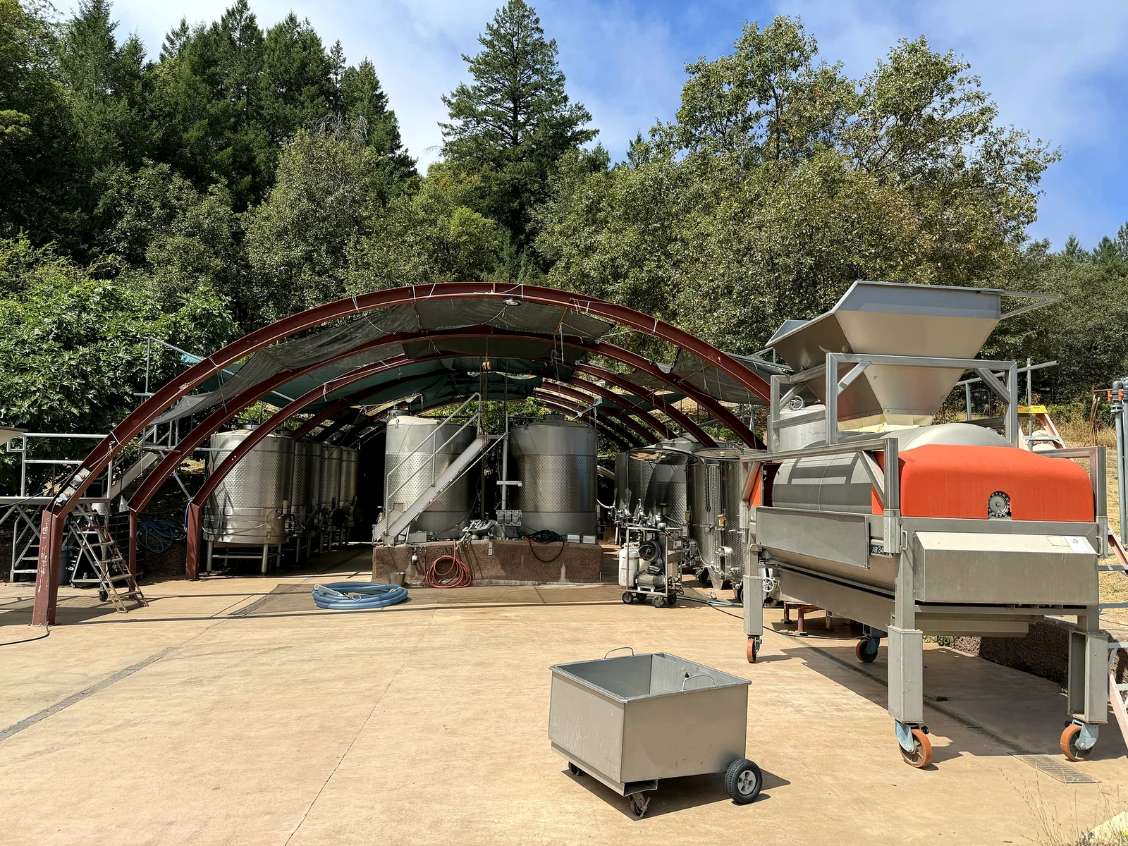 Open-air Dunn Vineyards crushpad with tanks, destemmer and curved red steel canopy