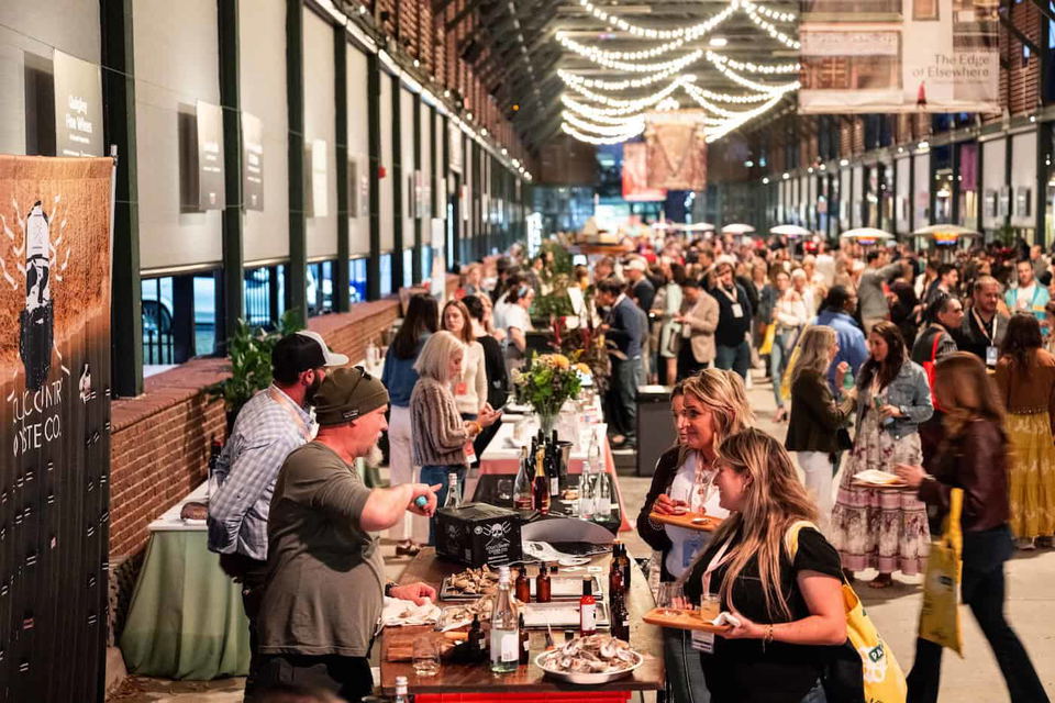 A busy indoor hall with guests at tasting stands during a previous Food and Wine Classic in Charleston