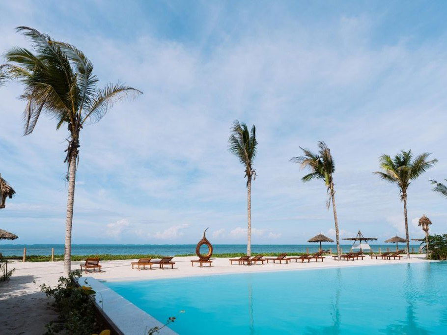 ENVI Paje Zanzibar offers a serene beachfront pool area with palm trees and ocean views.