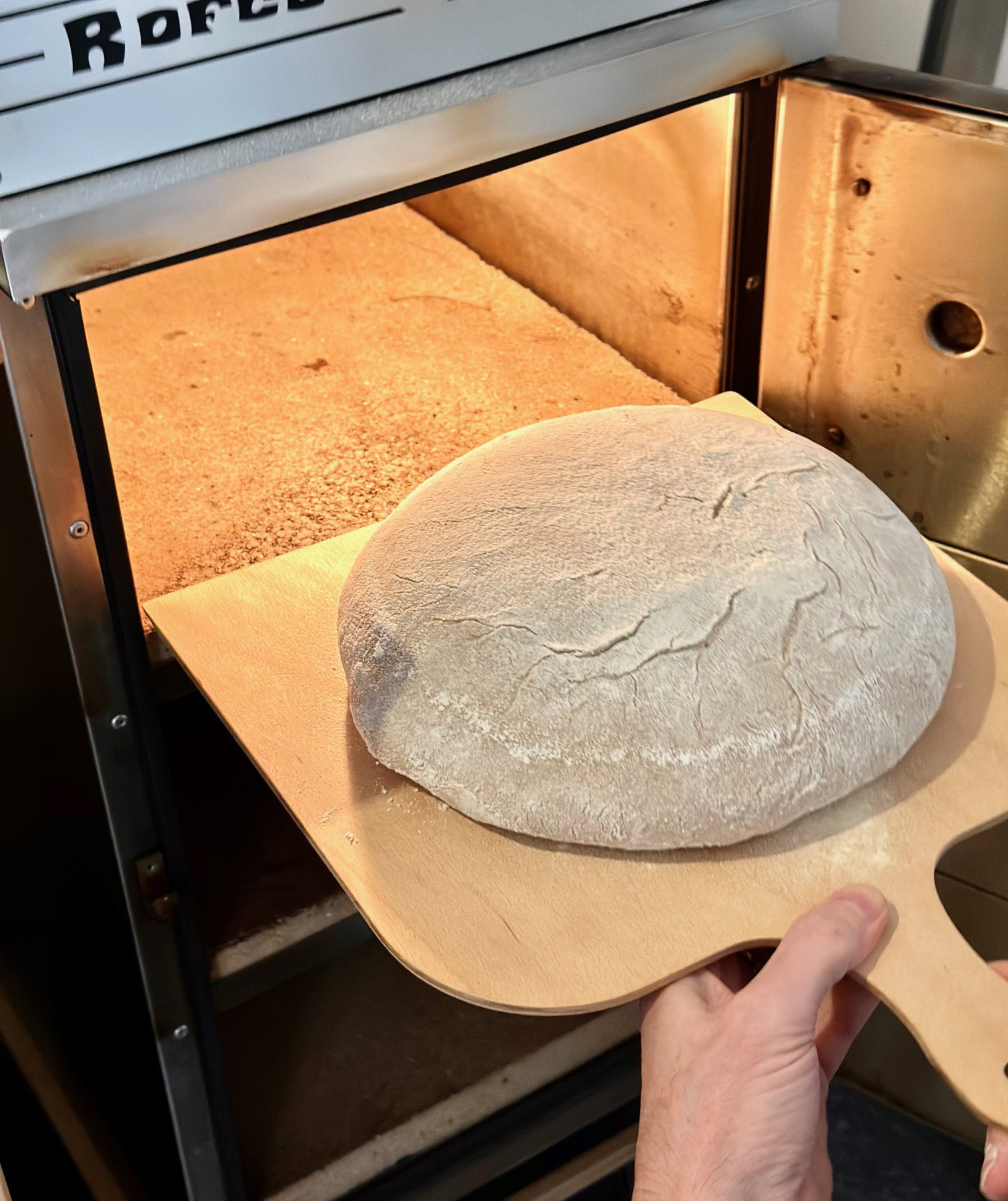 Baking bread in a commercial oven with a wooden peel.