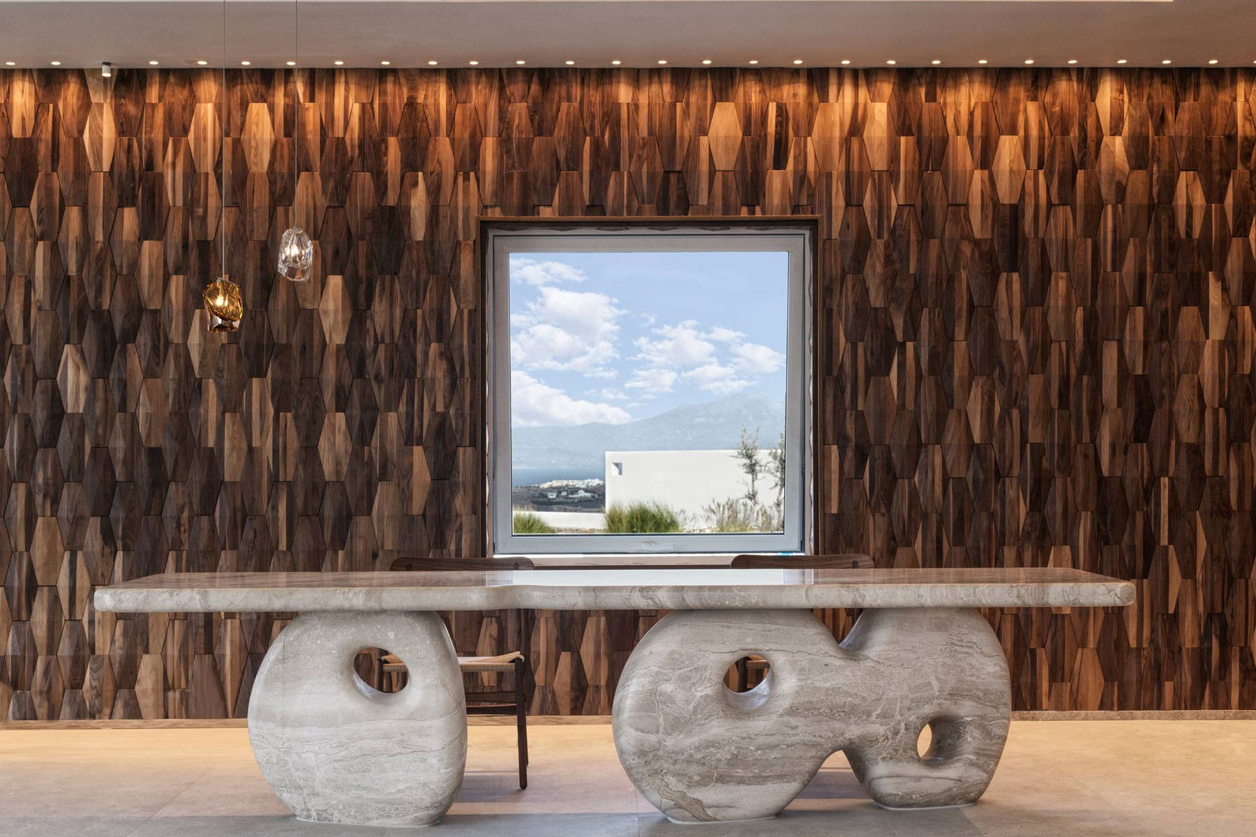 Fouquet's Mykonos: a luxury lobby with a textured wood wall, sculptural stone desk, and Aegean views.