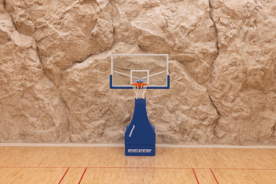 Fouquet's Mykonos: The rock-carved basketball court with a blue SPORTSYSTEM hoop and clear backboard.