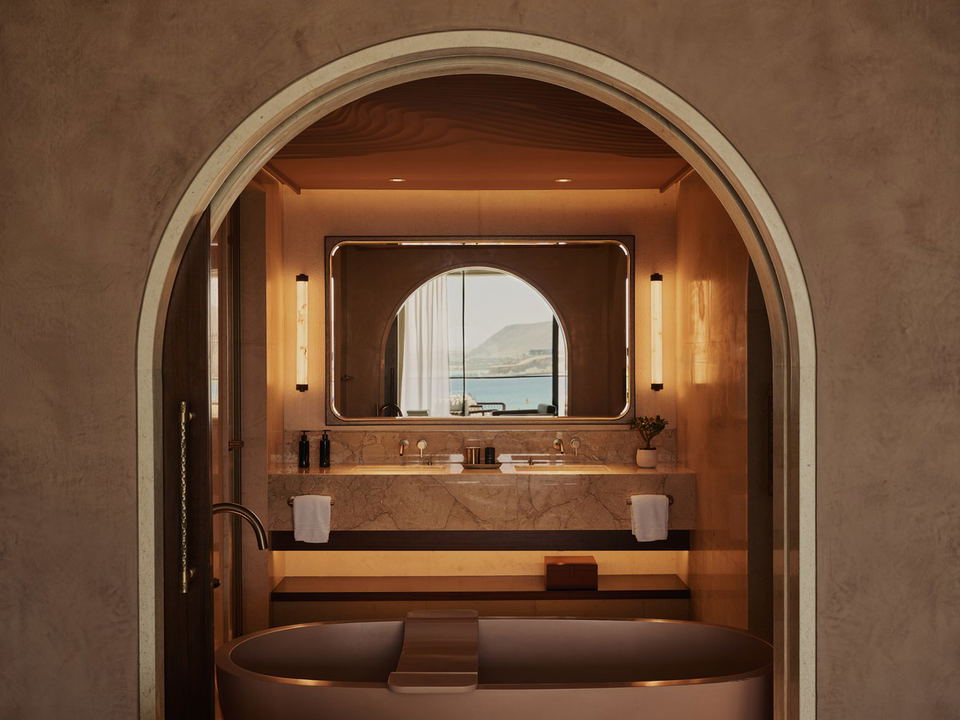 HYLIAA Wellness & Spa: A luxurious spa bathroom with a freestanding tub and marble vanity, reflecting a coastal view.