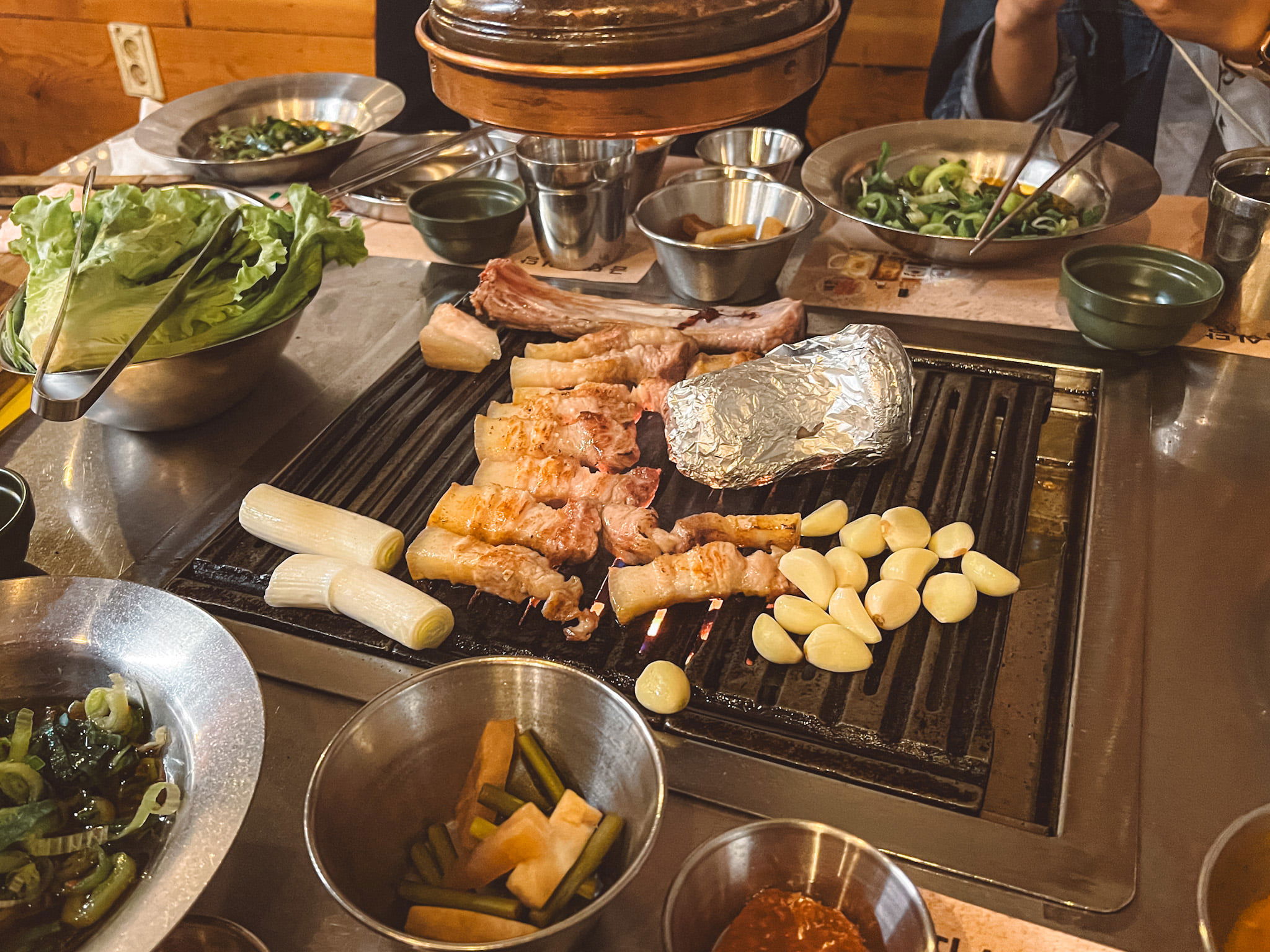 Geumdwaeji Sikdang's tableside grilling setup with YBD pork, garlic, and banchan, a core experience.