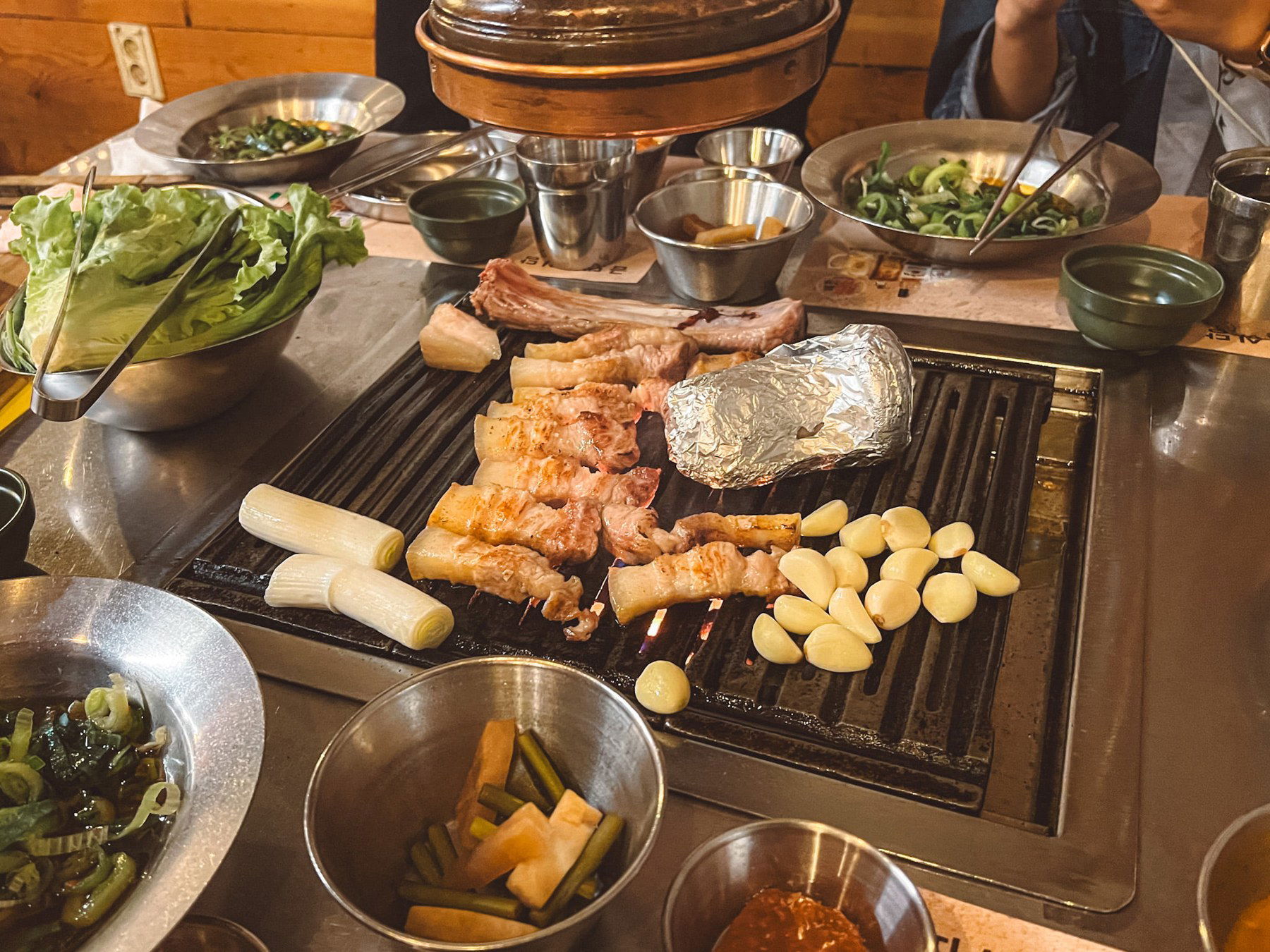 Geumdwaeji Sikdang's tableside grilling setup with YBD pork, garlic, and banchan, a core experience.