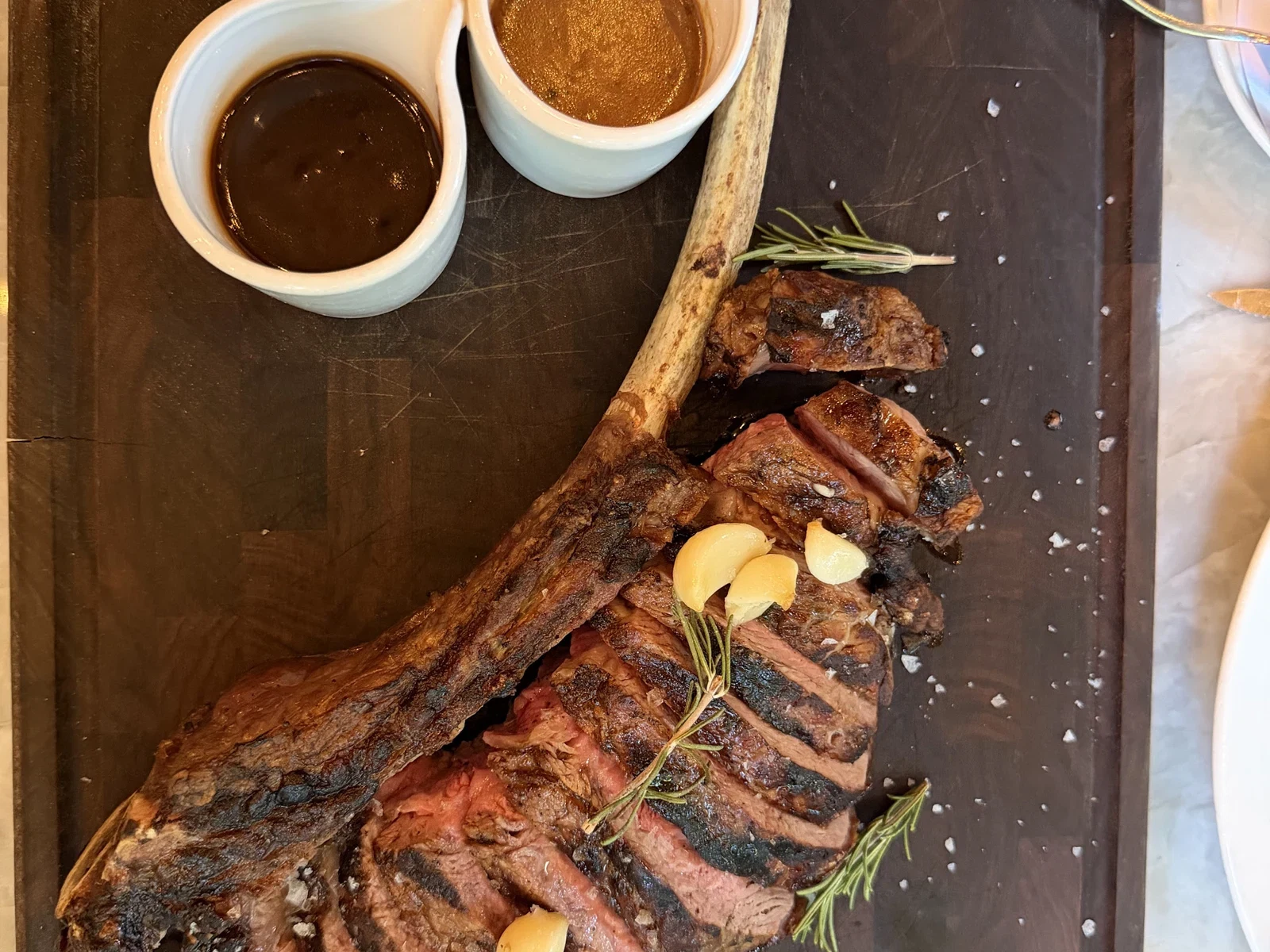 Sliced tomahawk steak with red chimichurri demi-glace and au poivre at Harvest Table