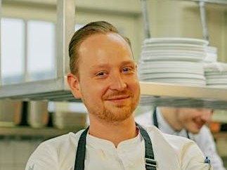 Hans-Martin Konrad, head chef at Hotel Adlon Kempinski Berlin, smiles from the kitchen.
