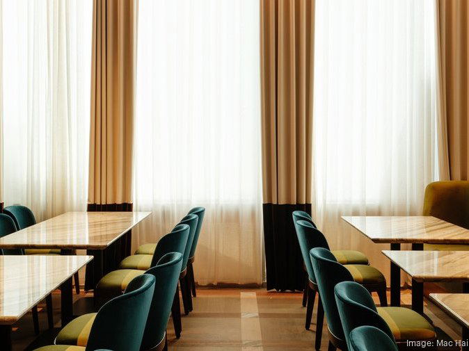 Kirkwood's elegant dining room features marble tables and teal chairs, with floor-to-ceiling sheer curtains.