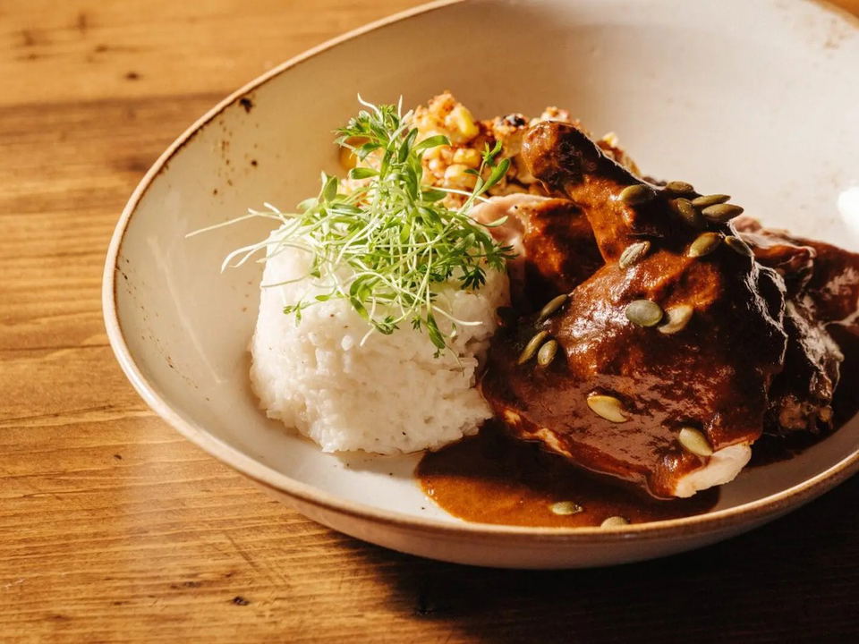 Exilio Latin Flair's chicken mole with rice, roasted elote, pumpkin seeds, and microgreens.