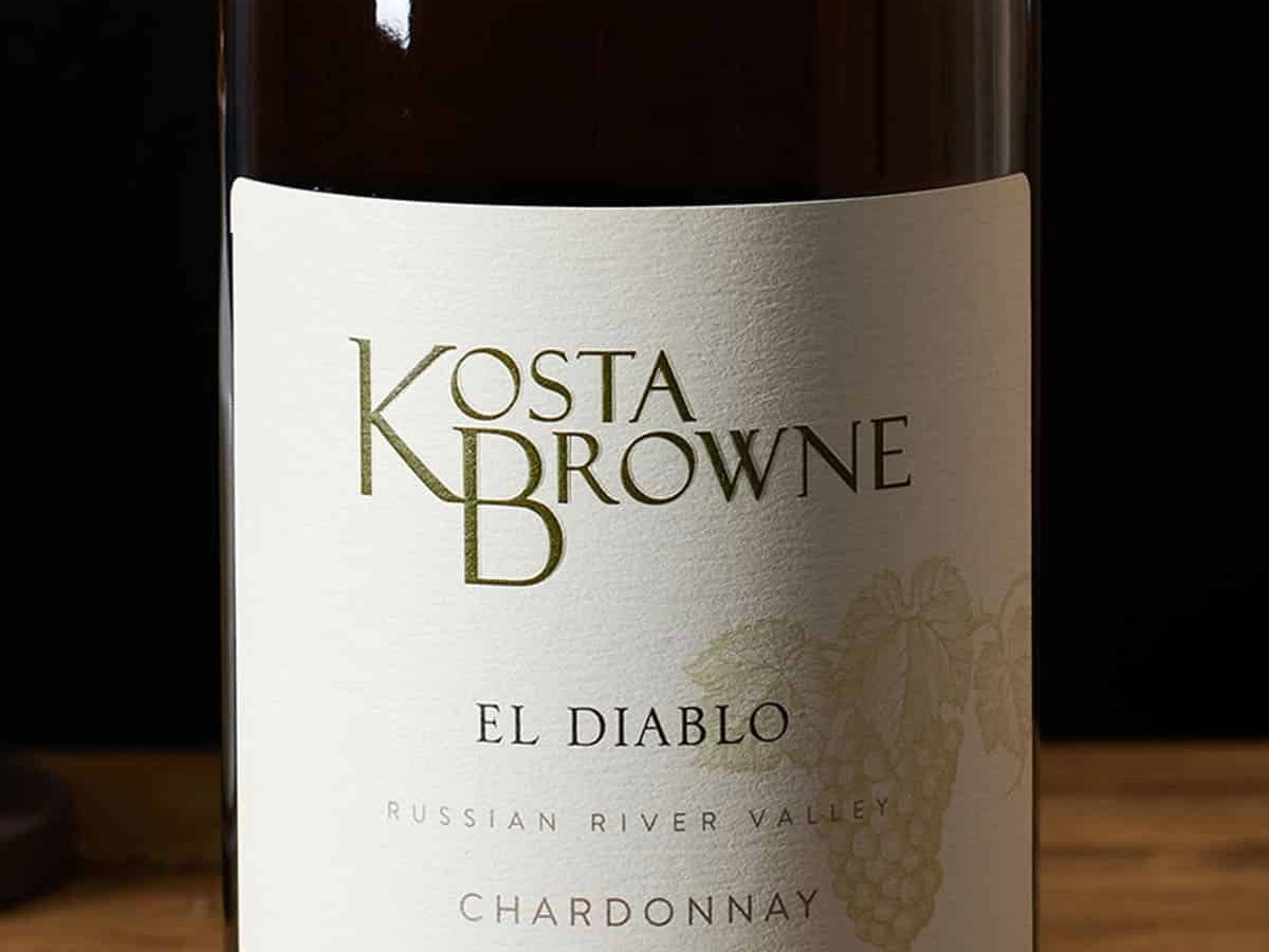 A close-up of a Kosta Browne 'El Diablo' Russian River Valley Chardonnay bottle, showing the label with gold lettering and a grape cluster.