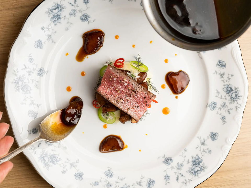 An A5 strip loin with black garlic, braised tendon, scallions, chili, and dill.