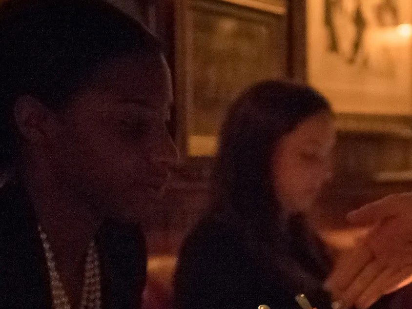 A dimly lit dining room at 4 Charles Prime Rib, with patrons seated at dark wood tables, enjoying a seafood tower.