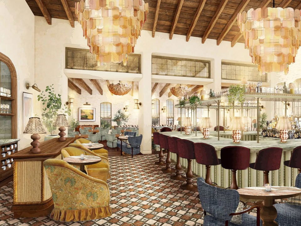 A rendered interior of Soho House Charleston, featuring a bar area with maroon velvet stools, mosaic tile floors, and large chandeliers.