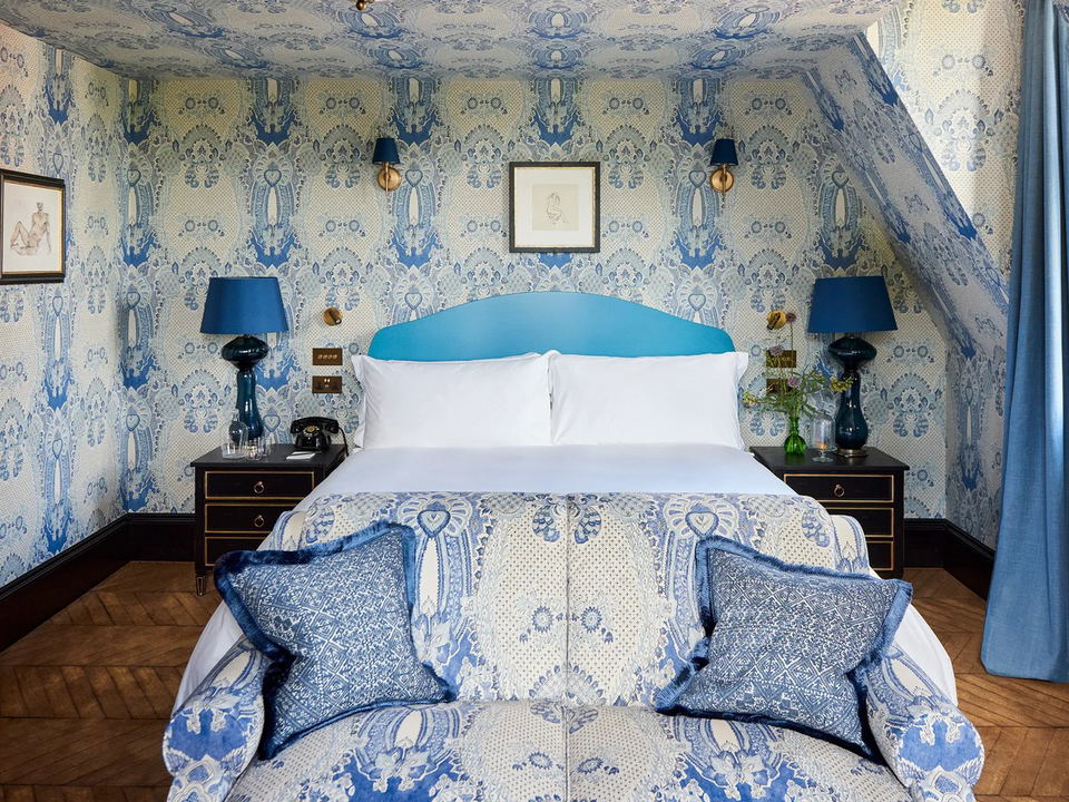 The Twenty Two offers a richly decorated hotel bedroom with floor-to-ceiling blue-and-white damask wallpaper.