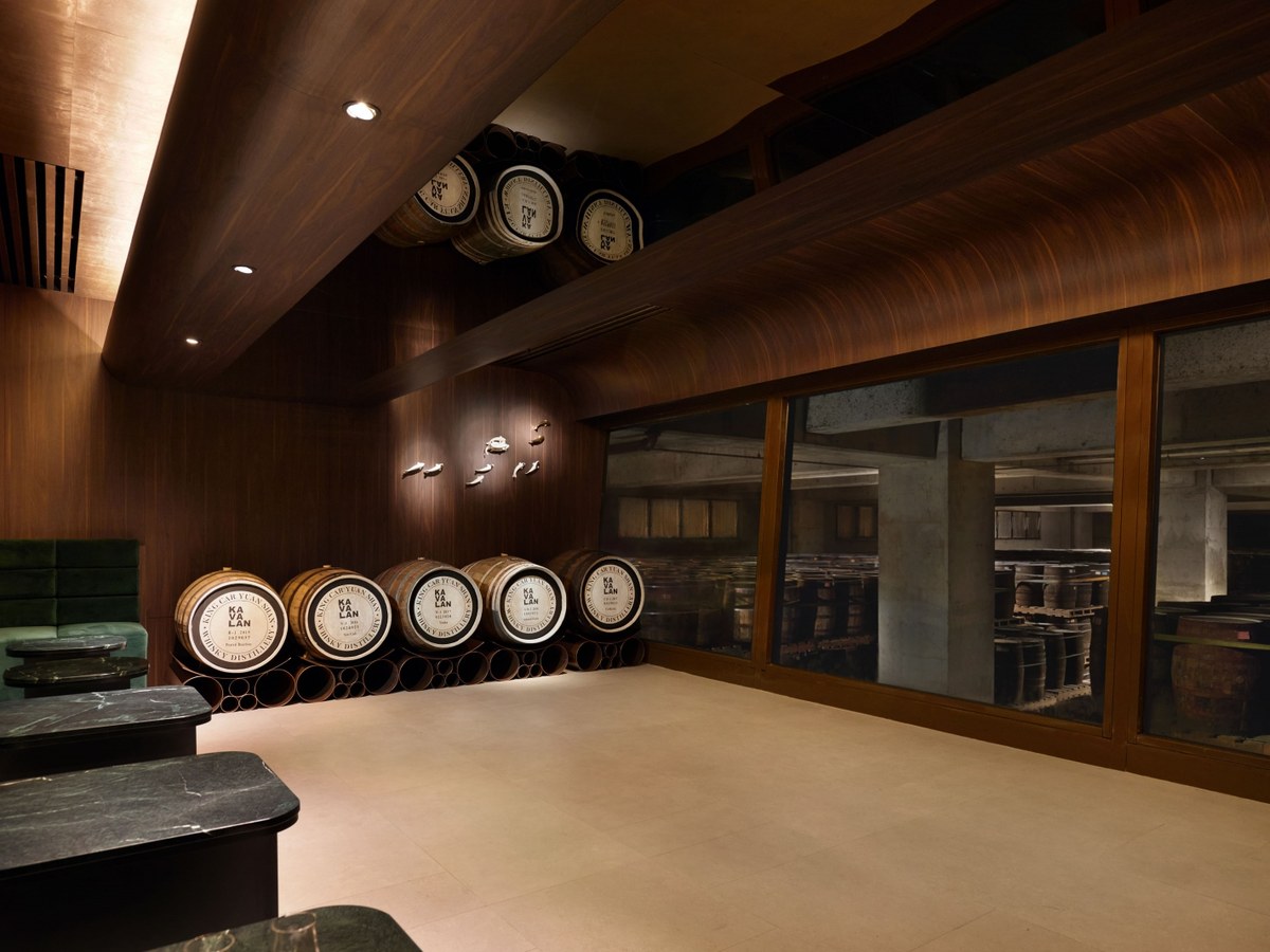 Interior of Kavalan Distillery's Warehouse Tasting Room, with oak casks labeled "KA VA LAN" and a large window overlooking a barrel warehouse.