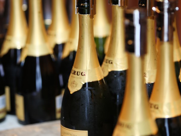 Multiple bottles of Krug Grande Cuvée Champagne, with gold foil necks and labels reading "KRUG" and "CHAMPAGNE KRUG GRANDE CUVÉE".