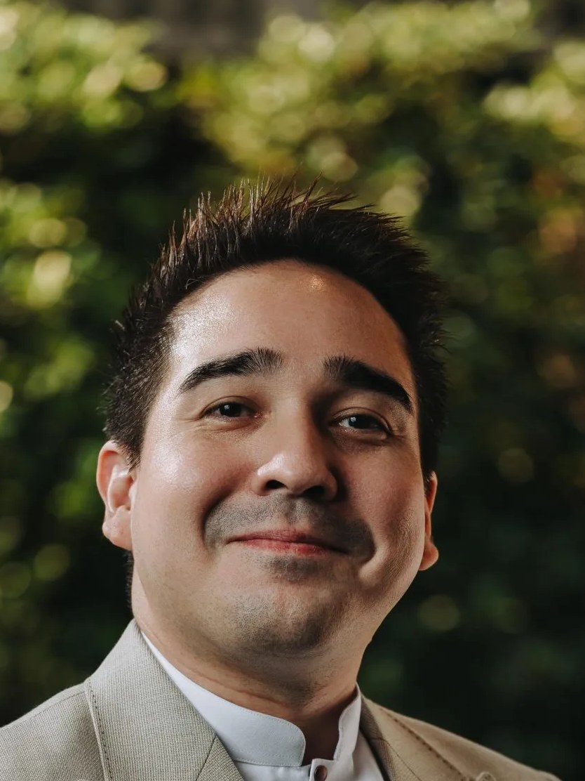 Thanakorn Bottorff, sommelier at Inddee, smiles in a formal outdoor portrait.