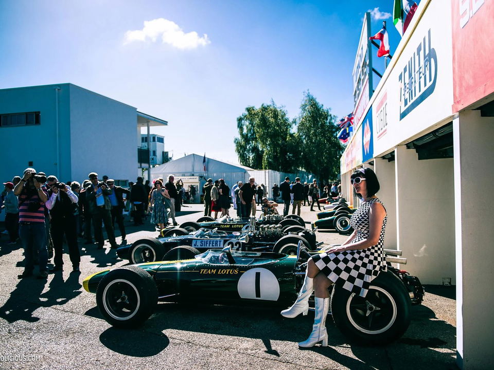 The Goodwood Revival paddock area: Vintage Team Lotus F1 cars and a 60s-style woman capture the era.