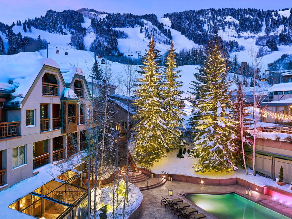 The Little Nell glows with festive lights, an outdoor pool, and ski slopes just steps away.