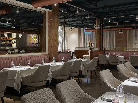 The elegant dining room of Indienne (River North) features plush, rose-colored banquettes and tables set with white tablecloths and delicate...