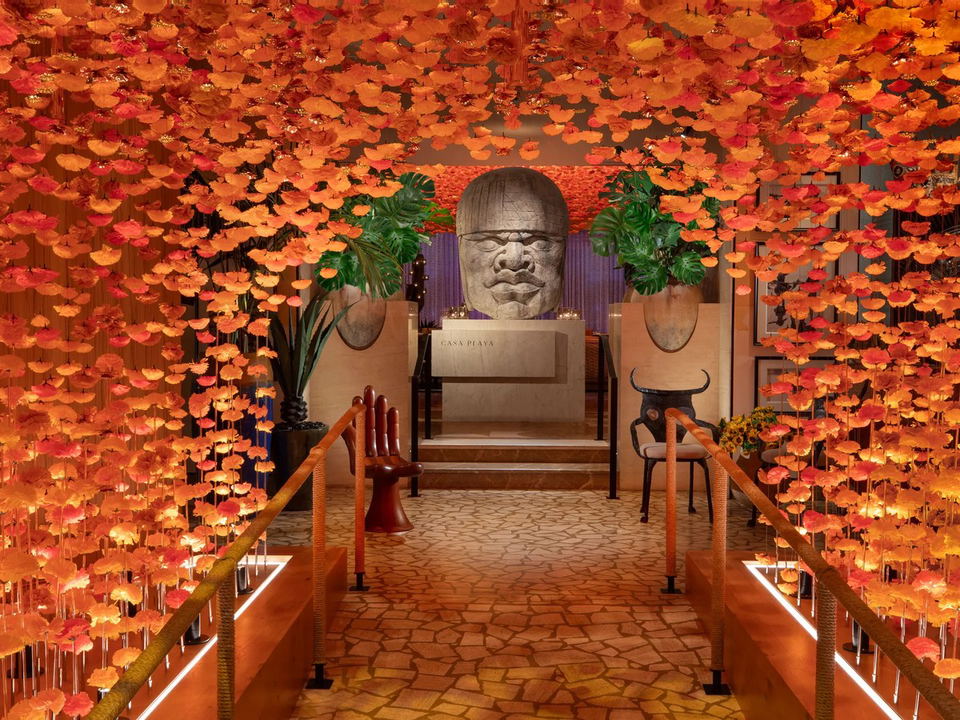 Casa Playa's vibrant entrance, with its floral tunnel and Olmec-style head, reflects Sarah Thompson's vision.