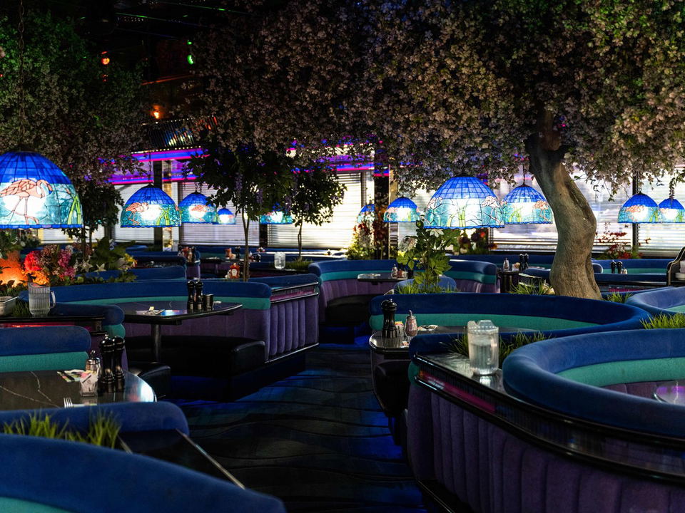 An atmospheric dining room interior at Bob Taylor's Ranch House, featuring circular blue and purple booths and decorative flowering trees.