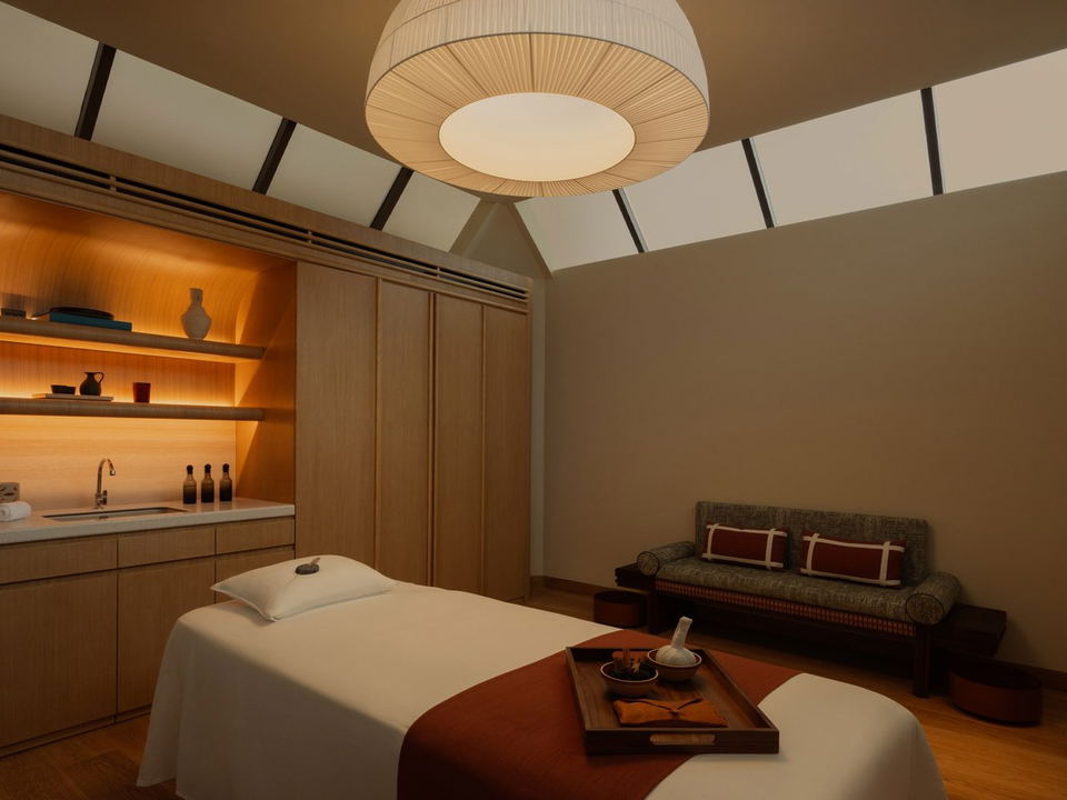 A spa treatment room with massage table, backlit shelving with sink, decorative ceiling fixture, and seating area; the source page (Sleeper Magazine a