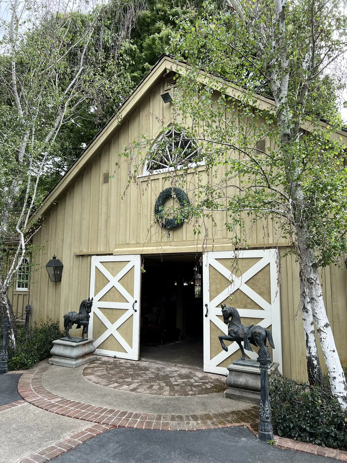 Meadowbrook Farm carriage house with open white barn doors and bronze horse sculptures