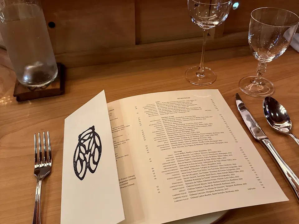 La Cigale dinner booklet open beside a place setting at the cypress counter