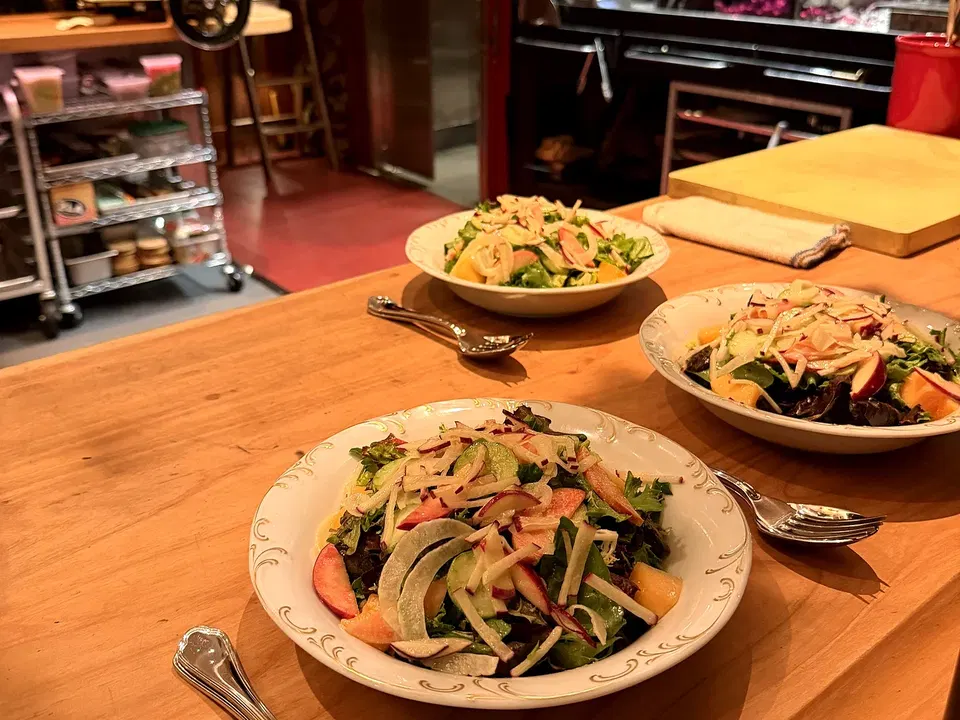 Shared platters of vegetables, salad and savory dishes spread across La Cigale’s counter