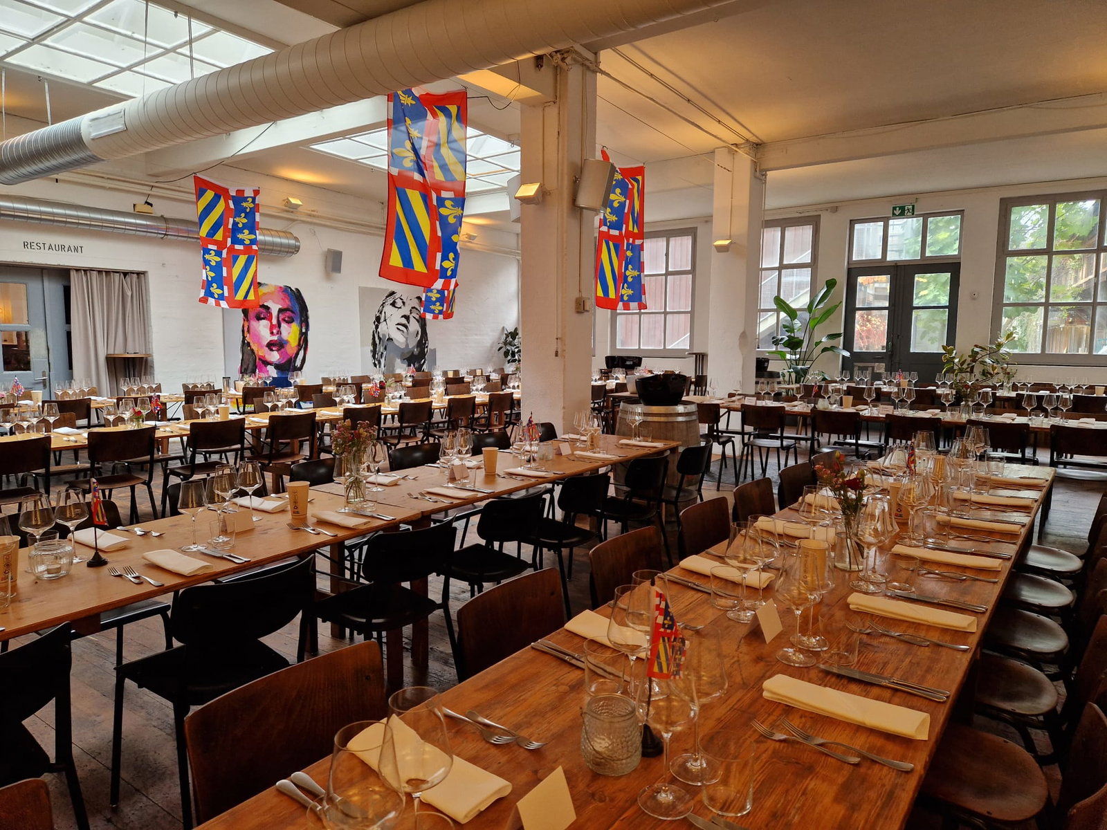 A Brief History of La Paulée showcases a large hall adorned with vibrant banners and set tables.