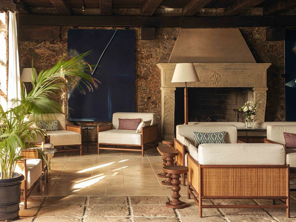 Rustic-luxe interiors at Le Dune Piscinas Ecoresort, featuring stone walls, exposed beams, and rattan seating.