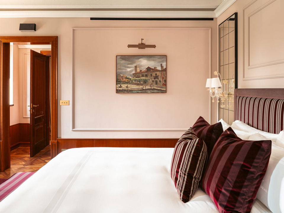 Locanda Cipriani Torcello suite with high-gloss wood paneling, herringbone parquet, and Murano glass fixtures.