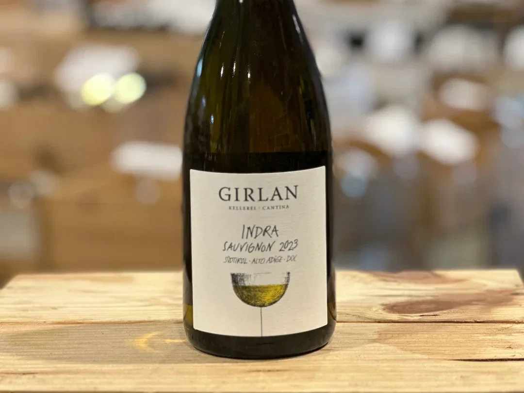 A bottle of Girlan Indra Sauvignon 2023 white wine with a black foil top and white label from Südtirol-Alto Adige DOC, northern Italy.