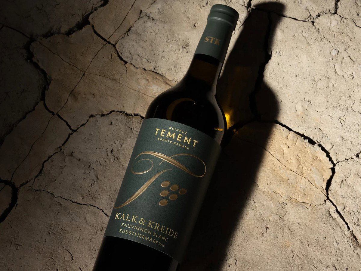 A bottle of Weingut Tement 'Kalk & Kreide' Sauvignon Blanc Südsteiermark DAC lies on a cracked, dry, light-colored surface.