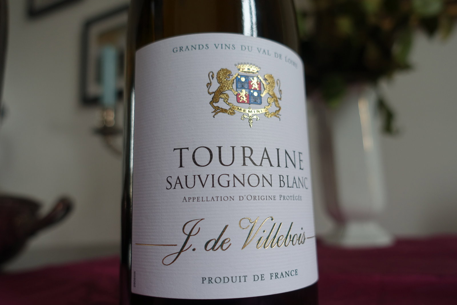 A close-up of a Touraine Sauvignon Blanc wine bottle, featuring a white label with gold text and a detailed coat of arms.