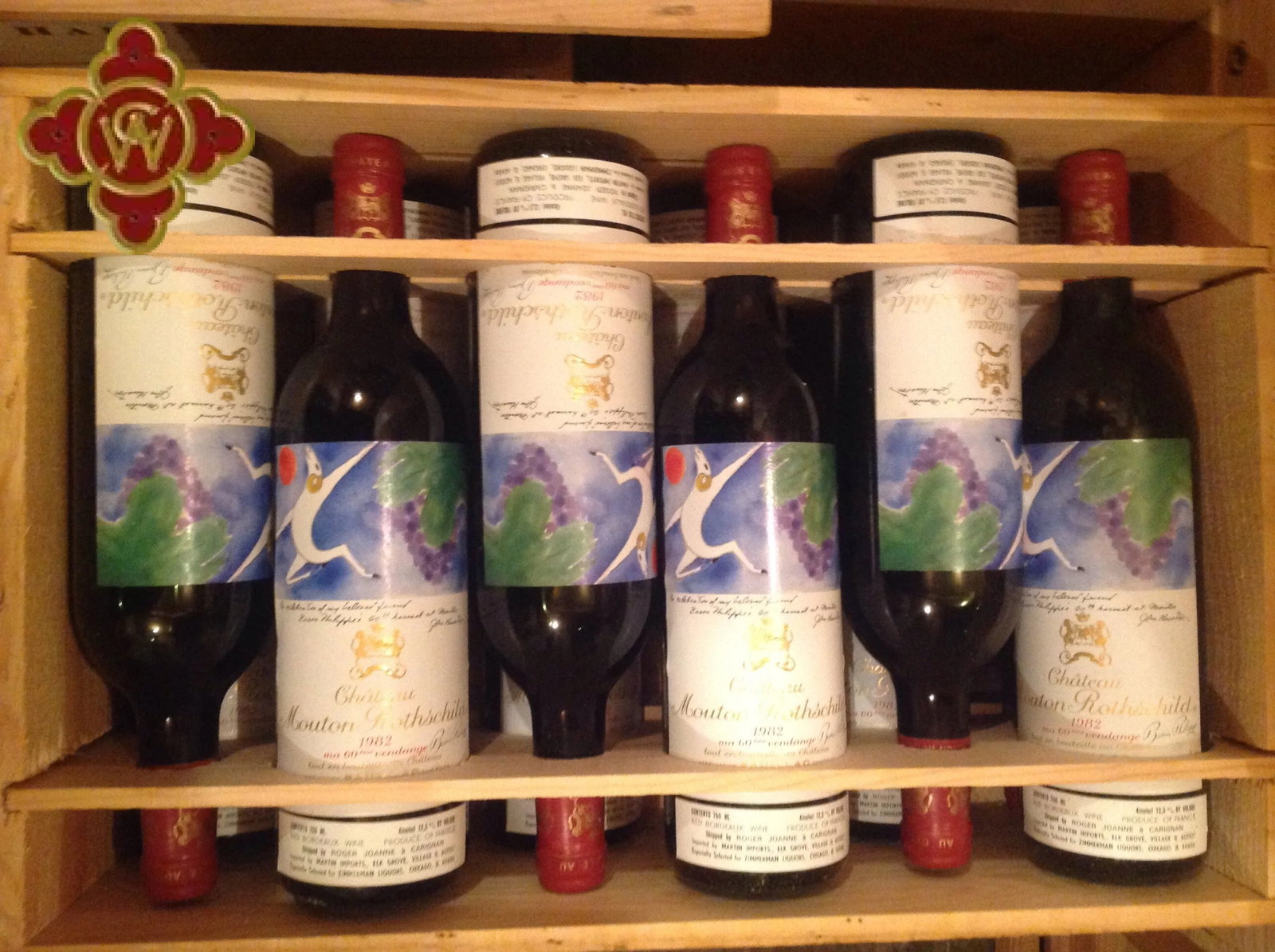 Wooden wine storage rack displaying multiple bottles of Château Mouton Rothschild 1982 in original wooden cases (OWC), with the distinctive artistic l