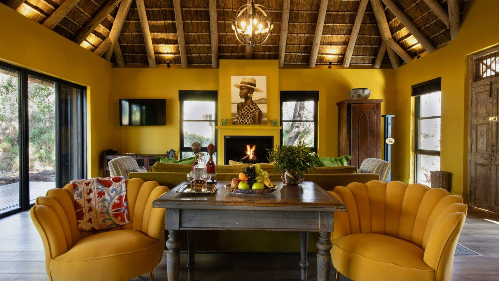 Waterside at Royal Malewane's lounge features bold yellow walls, a thatched roof, and mustard velvet chairs.