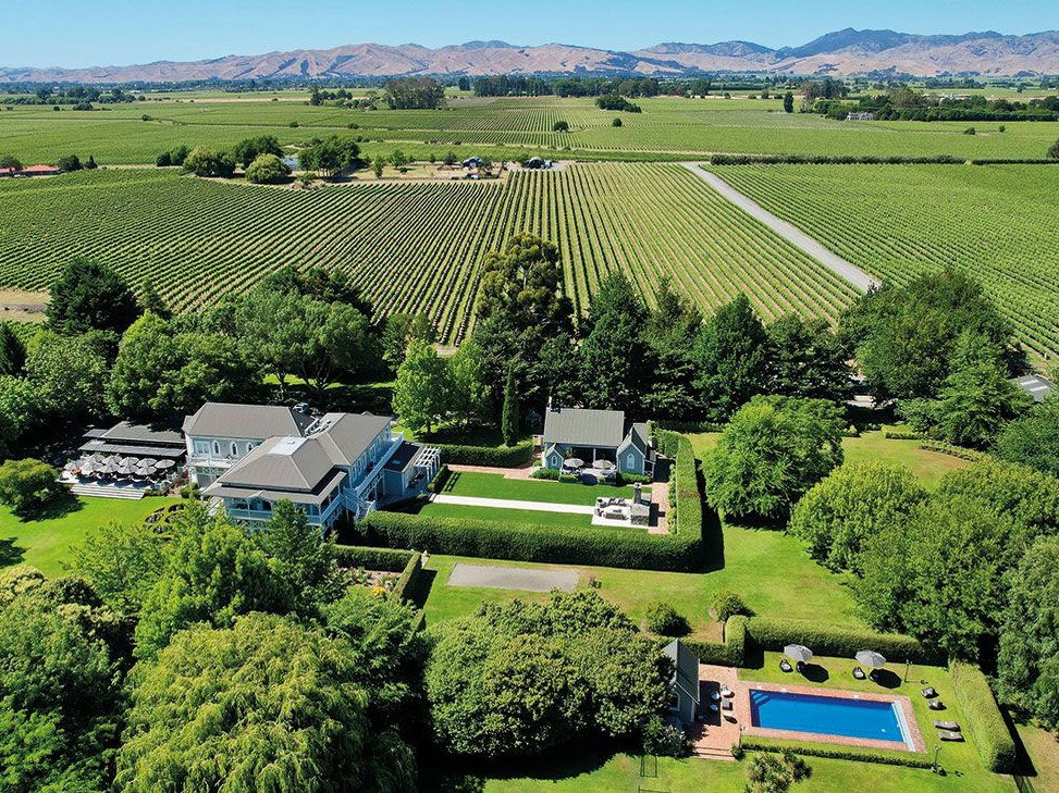 An aerial view of The Marlborough Boutique Hotel and Vineyard, showing a large manor house, a smaller guesthouse, a swimming pool, and rows of