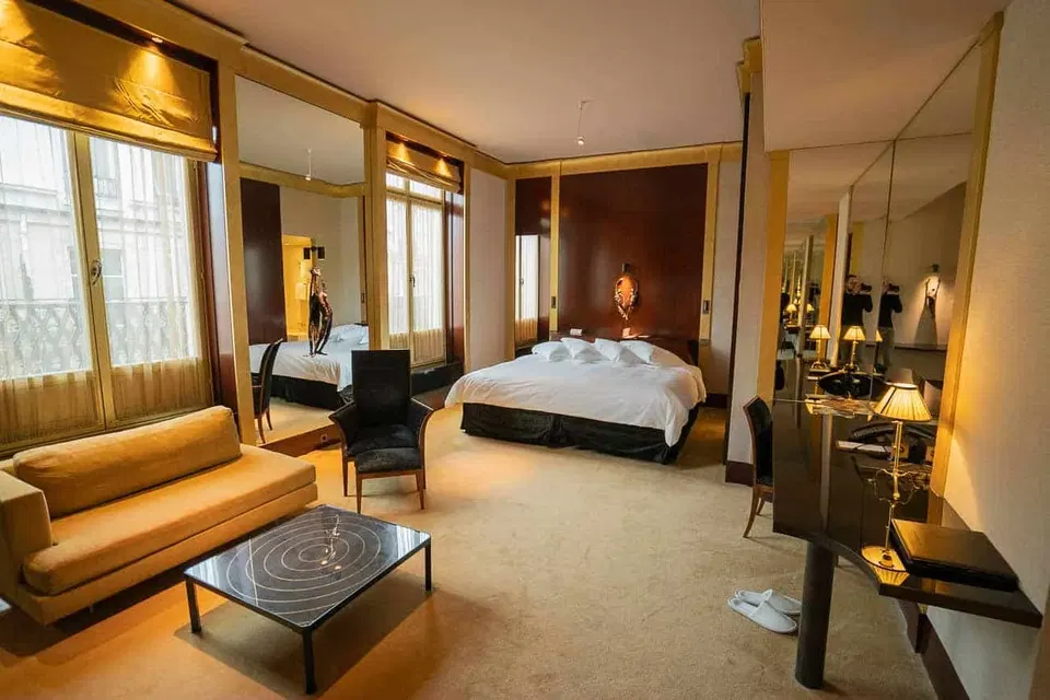 Park Hyatt Paris-Vendôme luxury suite interior with king bed, leather sofa, and warm gold lighting.
