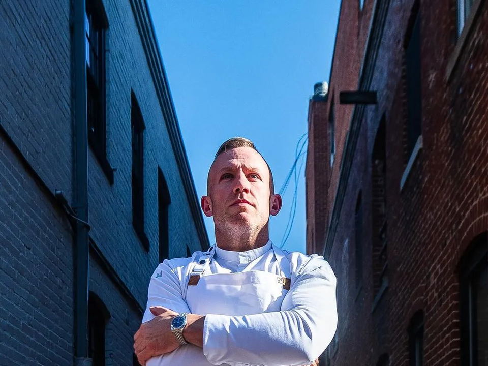 Ox & Olive's chef stands in the Georgetown alley, flanked by the steakhouse's signage.