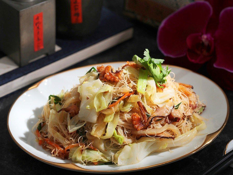 A plated dish from Essence restaurant featuring glass noodles, shrimp, cabbage, and garnishes, sourced from the Michelin Guide page for Essence in Que