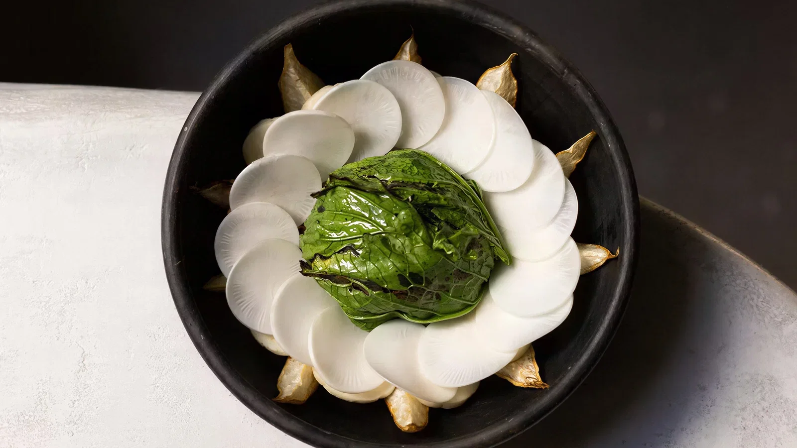 A vibrant dish from Meteora Los Angeles, featuring a green leafy center surrounded by white slices.