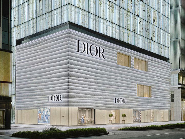 Exterior architectural photograph of the House of Dior Shinsaibashi building in Osaka, showing the distinctive white ribbed facade with DIOR signage; 