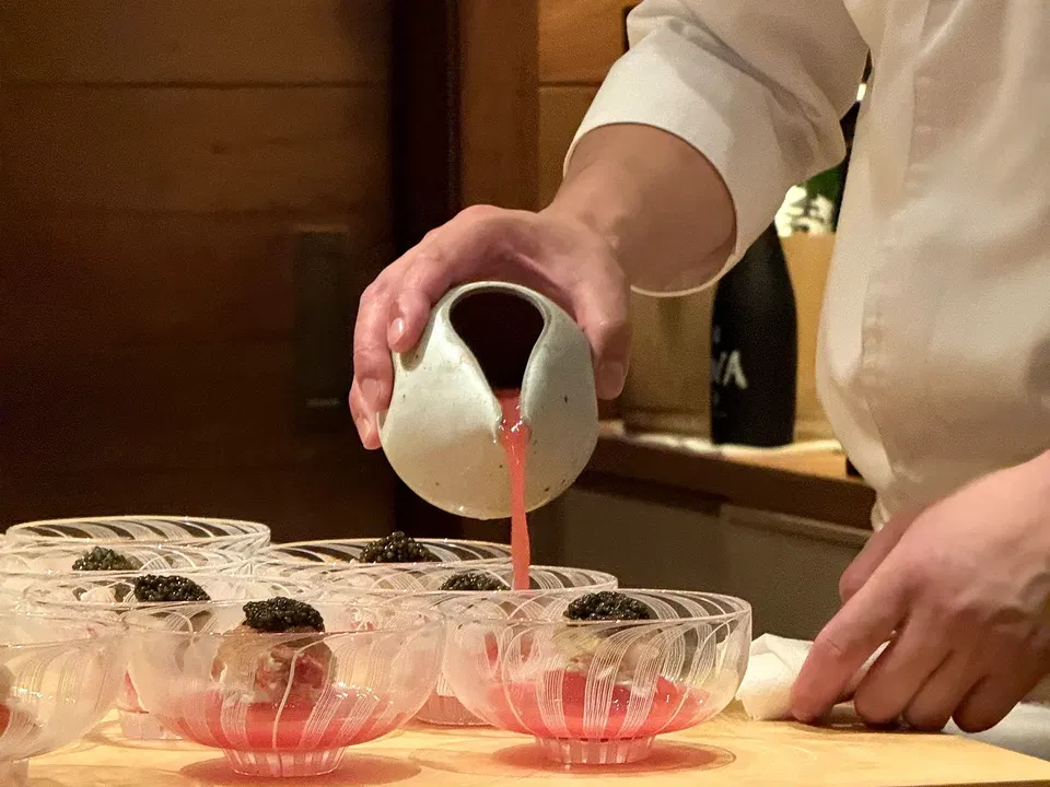 Sauce being poured into fluted glass bowls for Muku’s king crab sakizuke