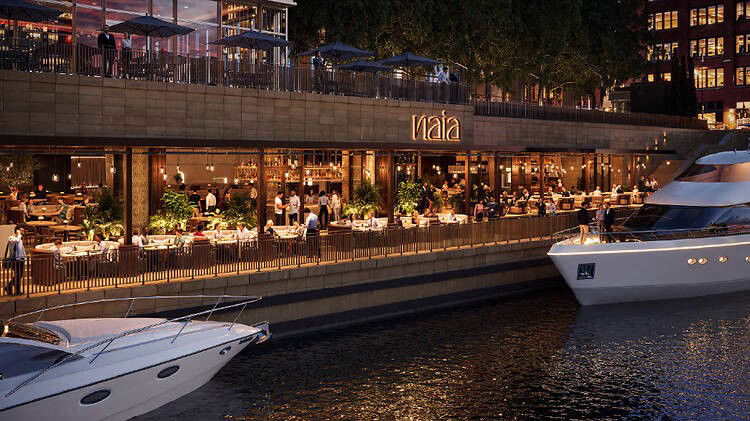 Naia Chicago's vibrant waterfront dining, with boats docked along the Chicago River and the downtown skyline beyond.